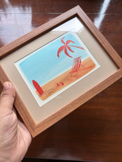 A wooden picture frame containing a beach illustration with a palm tree, chair, surfboard, and sand.