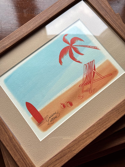 A framed art print depicting a minimalist beach scene with a red palm tree, red surfboard, striped beach chair, on a sandy shore under a light blue sky, presented in a wooden frame with a beige mat.