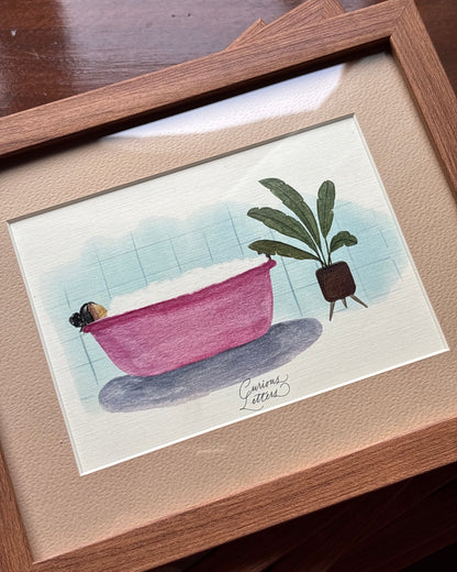 A framed watercolor painting of a girl in a pink bathtub full of soap bubbles, placed next to a potted plant, presented in a wooden frame.